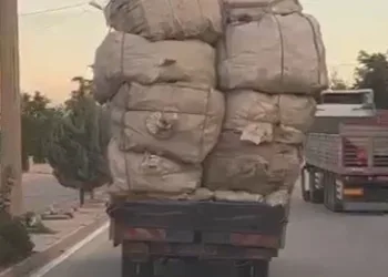 Kamyonetteki yükün üzerindeki çocukların elektrik tellerine çarpmamak için eğilerek gitmeleri kamerada