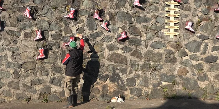 Taş duvarı saksı olarak kullandığı çizmelerle renklendirdi